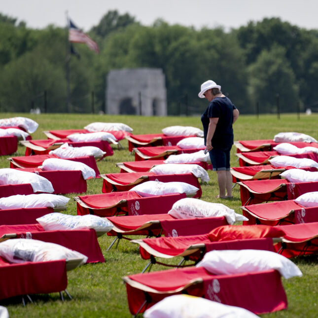 A person walks through the installation of 300 red cots, looking at text written over the pillows — first opinion coverage from STAT