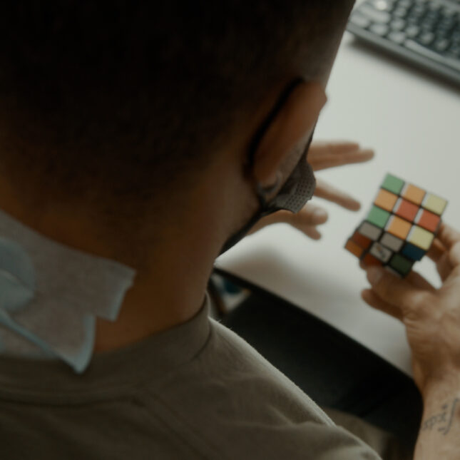 A masked person wears Onward Medical’s non-invasive spinal cord stimulator, solving a Rubik's cube — health tech coverage from STAT